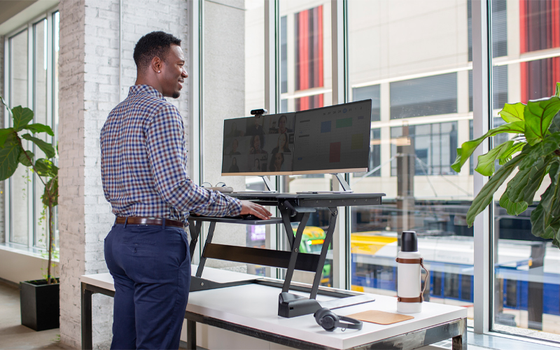 Man Stood at desk using and Ergotron standing desk product