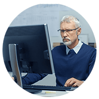 Older businessman in glasses on desktop computer
