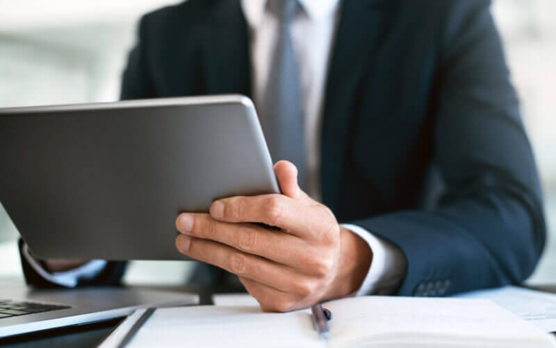 Businessman working in financial services company views reports on tablet device