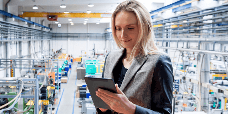 Businesswoman tracks orders on tablet device in manufacturing facility
