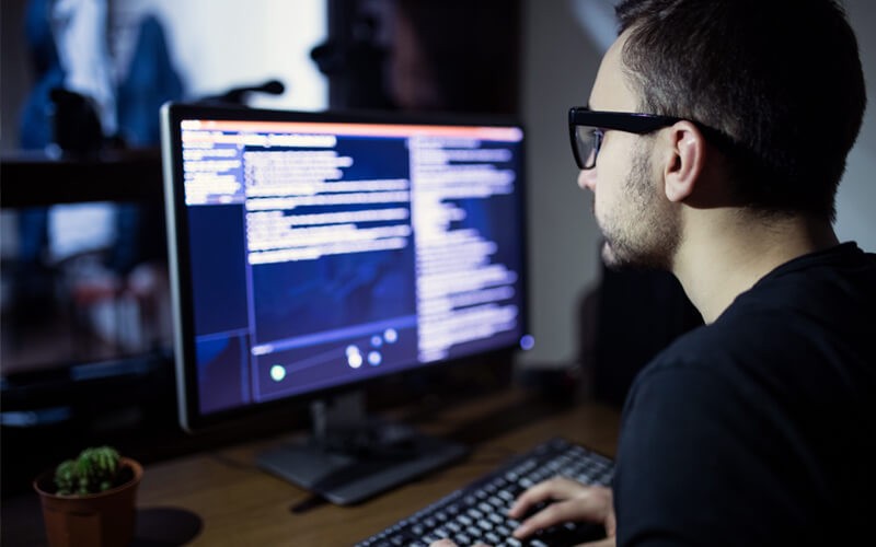 Programmer coding on desktop at night