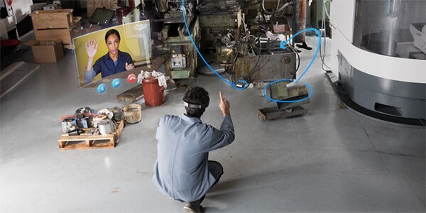 Manufacturing worker using a Microsoft HoloLens to show a projection of a teammate collaborating with him