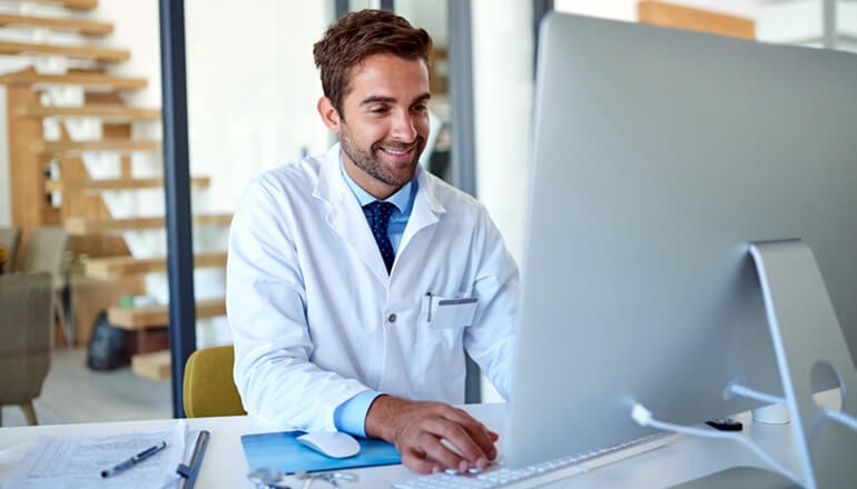 Doctor looking at patient data on desktop computer