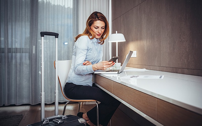 Smiling businesswoman in hotel room working remotely 