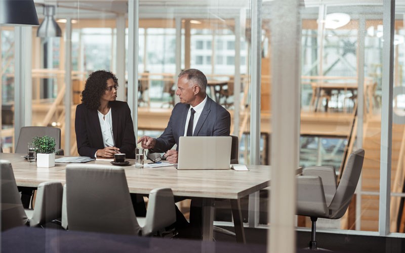 Secure encrypted traffic across your network Two coworkers in office meeting room discussing over laptop device