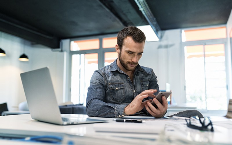 Safeguard your data. Business professional checking email on smart phone at his desk