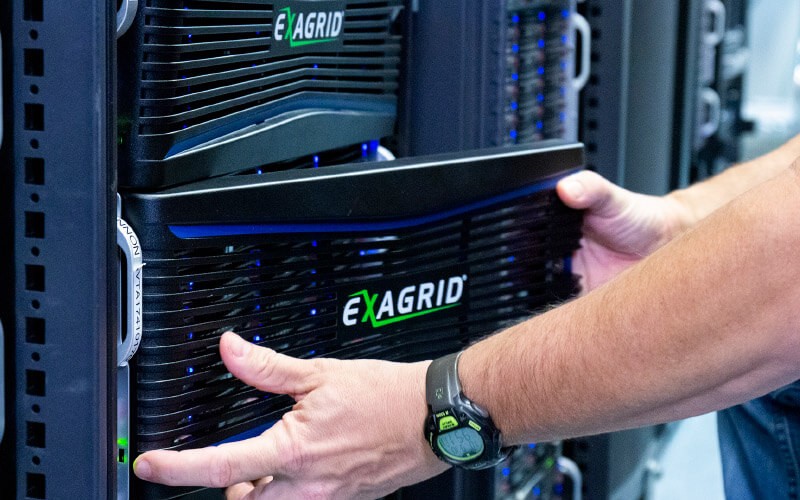 Innovative, tiered backup storage IT professional inserting disk on data storage