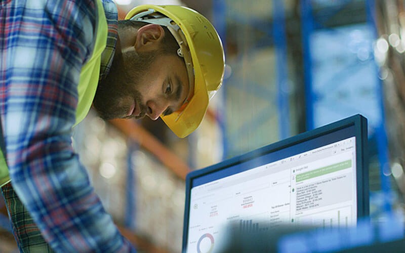 Qlik Sense Cloud Business Qlik lifestyle man working on laptop in warehouse