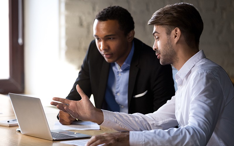 Get a complete and comprehensive vulnerability management solution that eliminates the need for multiple software products Employees discussion using laptop