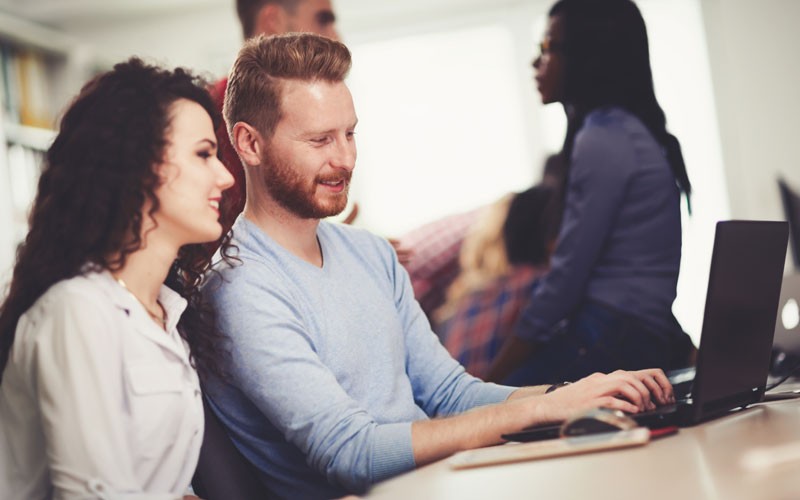 Smartsheet enables team to be more collaborative Two employees collaborating at laptop