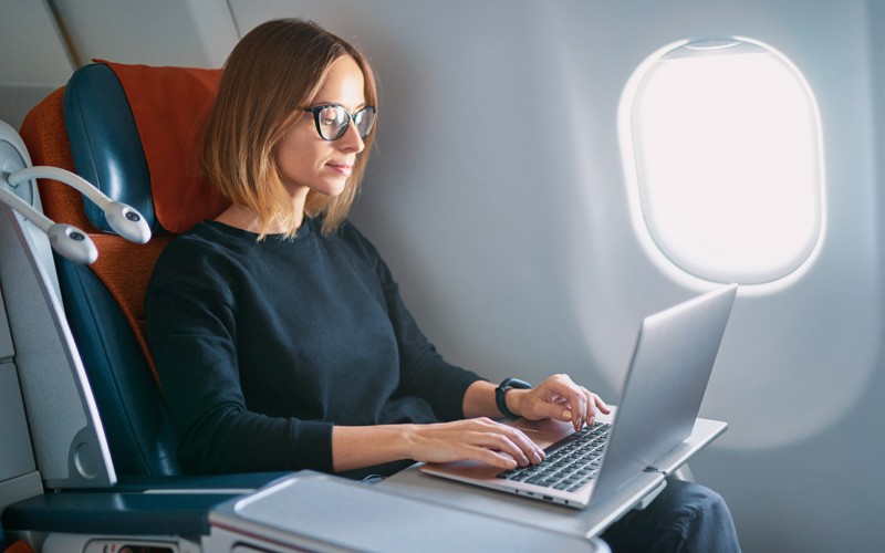 Business woman on laptop device on airplane
