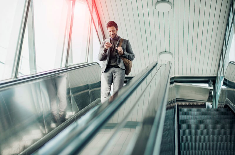 Business executive using mobile app on smart phone on escalator